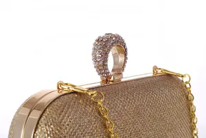 Detailed view of women evening rhinestone clutch bag with gold ring handle and chain strap.