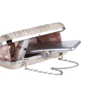 Detailed view of elegant pleated evening clutch bag with chain strap and rhinestone pearl clasp.