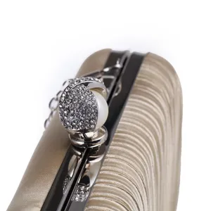 Close-up of champagne pleated evening bag with rhinestone pearl clasp and chain strap.