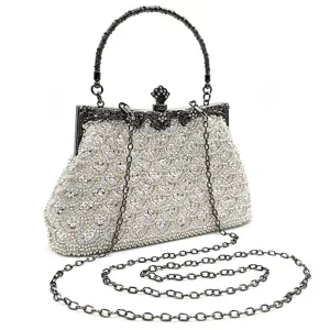 Closeup of exquisite beaded evening clutch bag with metal frame handle and chain strap for women.