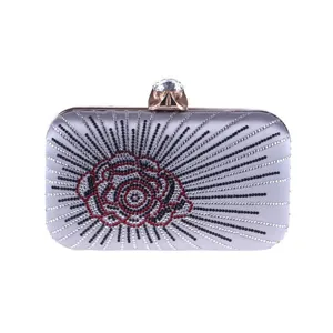 Silver satin evening clutch bag detail, rhinestone rose pattern and crystal clasp close-up.