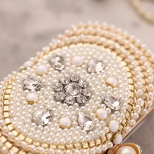 Detailed view of luxury pearl evening clutch bag with sparkling rhinestones and gold accents.