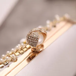 Exquisite rhinestone pearl clasp detail of women evening clutch bag, elegant gold hardware.