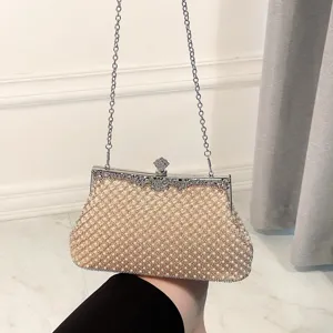 Close-up of elegant pearl-embellished evening clutch with metallic frame and chain strap.