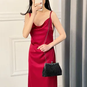 Black beaded evening bag with chain strap and crystal clasp, paired with elegant red dress.