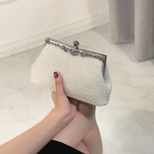 Detail shot of an elegant white pearl evening clutch bag with intricate silver metal clasp frame.