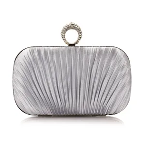 Silver pleated evening clutch bag detail showing exquisite rhinestone ring handle and texture.
