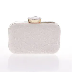 Bolso clutch de noche en encaje blanco, elegante marco de metal dorado y cierre de pedrería.