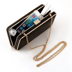 Detailaufnahme der schwarzen Abendtasche mit goldenem Metallrahmen und feiner Kette.