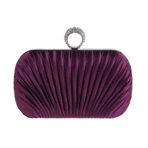 Detailed close-up of a purple pleated evening clutch purse with elegant rhinestone ring clasp.