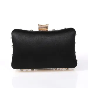 Detail view of black satin evening clutch featuring sparkling rhinestones and gold clasp.