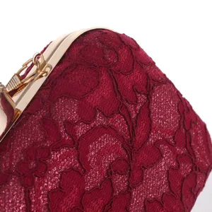 Detalle en primer plano del bolso de noche de encaje burdeos con elegante marco dorado.