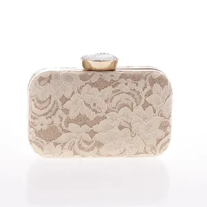 Exquisito bolso de mano de encaje beige con marco metálico y cierre de diamantes brillantes.