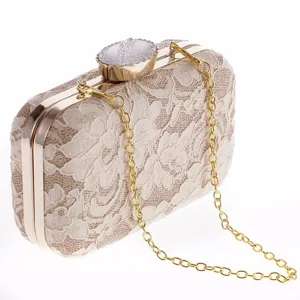Vista detallada del elegante bolso de mano de encaje beige con herrajes dorados.