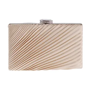 Detailed shot of a champagne pleated evening clutch with rhinestone clasp for women party.