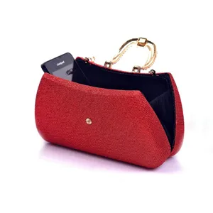 Red glitter evening clutch bag detail, gold-tone metal handle and compact structured design.