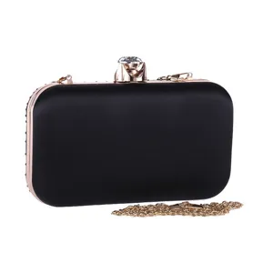 Detailed close-up of the black evening clutch showcasing the diamond clasp and gold chain.
