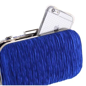 Close-up van blauwe geplooide avondtas, hardcase ontwerp met metalen framedetail.