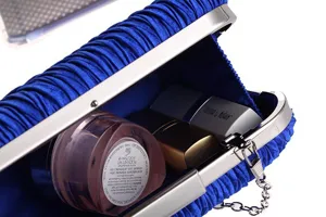 Gedetailleerd overzicht van blauwe geplooide avondtas binnenkapaciteit en satijnen textuur.