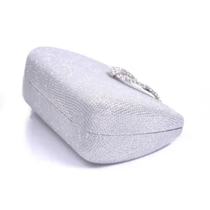 Detailed close-up of silver glitter evening clutch featuring sparkling crystal clasp ornament.