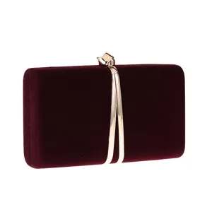 Burgundy velvet clutch bag detail, gold metal clasp and curve ornament texture closeup view.