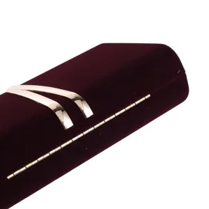 Detail view of burgundy velvet evening clutch bag, featuring metallic gold V accent and hinge.