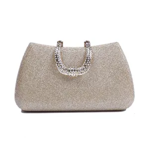 Close-up detail of the sparkling gold evening clutch bag with rhinestone handle decoration.