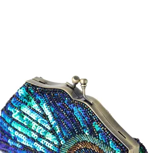 Close-up detail of vintage sequin beaded clutch bag with metal clasp and peacock pattern.