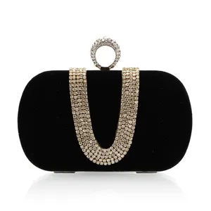 Black velvet evening clutch detail showing rhinestone U-shaped strap and sparkling ring clasp.