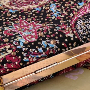Close-up detail of rhinestone evening clutch bag with colorful floral print and metal frame.