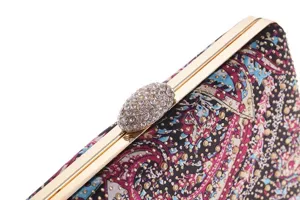 Close-up detail of women evening clutch bag, ornate colorful print with rhinestones and gold frame.