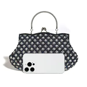 Beaded evening bag with metal handle and elegant clover pattern, shown with phone for scale.