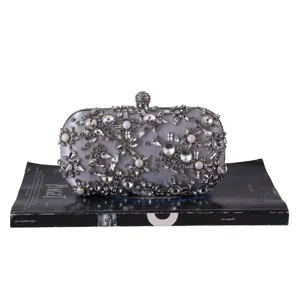 Detailed close-up of silver evening clutch bag adorned with sparkling crystals and pearls.