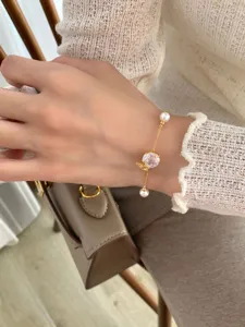 Delicate gold-tone bracelet detail featuring a sparkling crystal and cute butterfly charm.