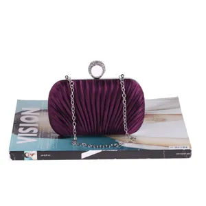 Detailed view of a purple pleated evening clutch bag with diamond ring handle and chain.