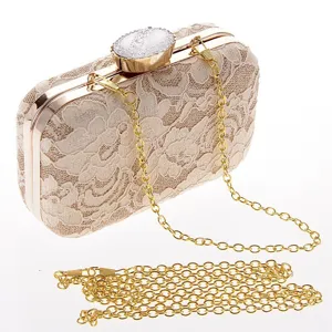 Primer plano del elegante bolso de mano de encaje beige con cadena dorada y cierre.