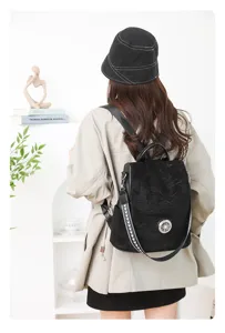 Detail view of stylish black women's backpack with wide shoulder strap and metal buckle.