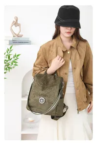 Detail view of olive green suede backpack with stylish circular buckle and strap.