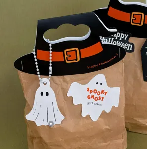 Close-up detail of Halloween witch hat paper bag handle and ghost tag, festive craft decor.