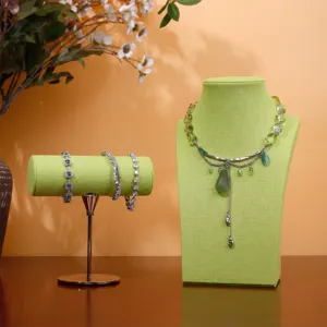 Set espositore per gioielli in tessuto verde con busto per collana e supporto per bracciali.