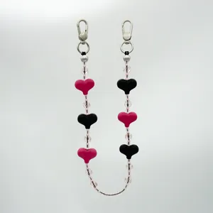 Vista detallada de la cadena de teléfono con cuentas de corazón rosa y negro y doble cierre.