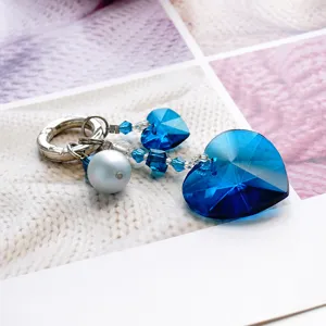 Détail de porte-clés cœur en cristal bleu avec perle et fermoir argenté pour les sacs.