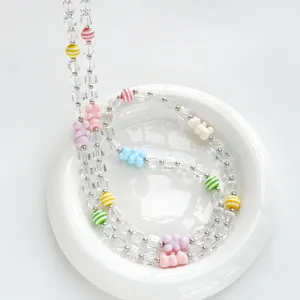 Dettaglio laccio per telefono con perline di orsetto colorate, cristallo e perle a righe.