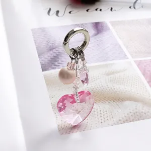 Gros plan d'un pendentif en cristal rose en forme de cœur avec perle et fermoir en métal.