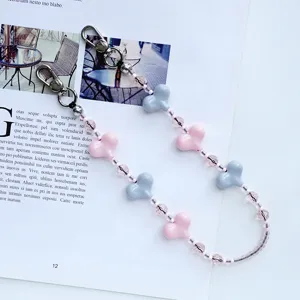 Detalle de la cadena para teléfono de cuentas de corazones rosas y azules con cristales brillantes.