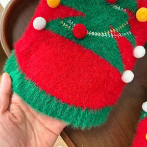 Primer plano detallado del suéter navideño esponjoso para mascotas con pompones coloridos y bordado.