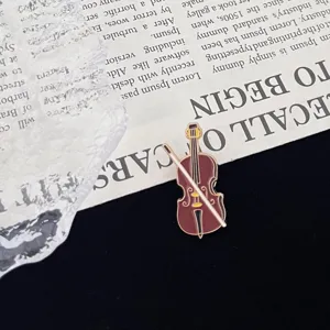 Close-up of a vintage violin enamel brooch pin with bow, artistic music badge accessory.