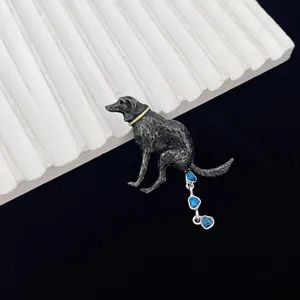 Novelty dog brooch detail showing quirky black metal design with blue heart rhinestone tassel.