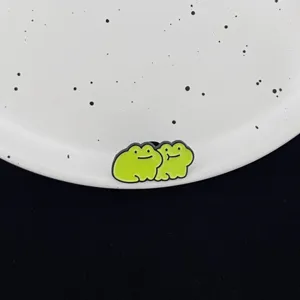Cute green frog enamel pin detail shot, perfect cartoon animal fashion accessory for apparel.