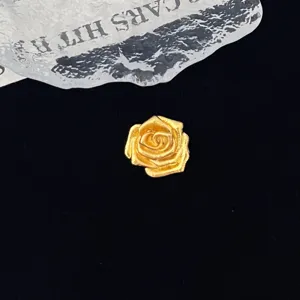 Detailed close-up of a vintage gold rose flower brooch accessory showing intricate petal texture.
